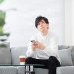 スマホをもって悩む男性